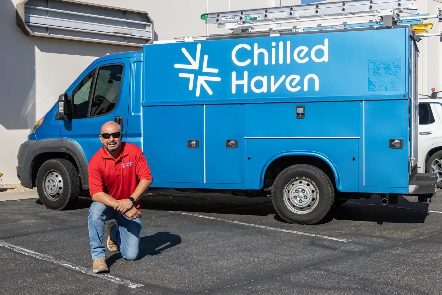 Man posing next to a blue Chilled Haven truck in a parking lot.