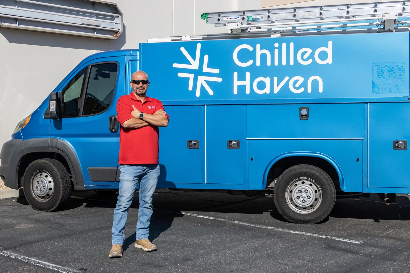 Man in red shirt stands confidently by a blue Chilled Haven van.