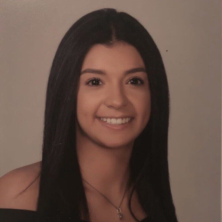 Portrait of a young woman smiling with long dark hair.